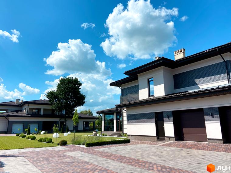 Котеджне містечко КМ Franko River Club з сучасними будинками та доглянутою прибудинковою територією під блакитним небом з хмарами. Зовнішній вигляд будинків та ландшафтний дизайн.