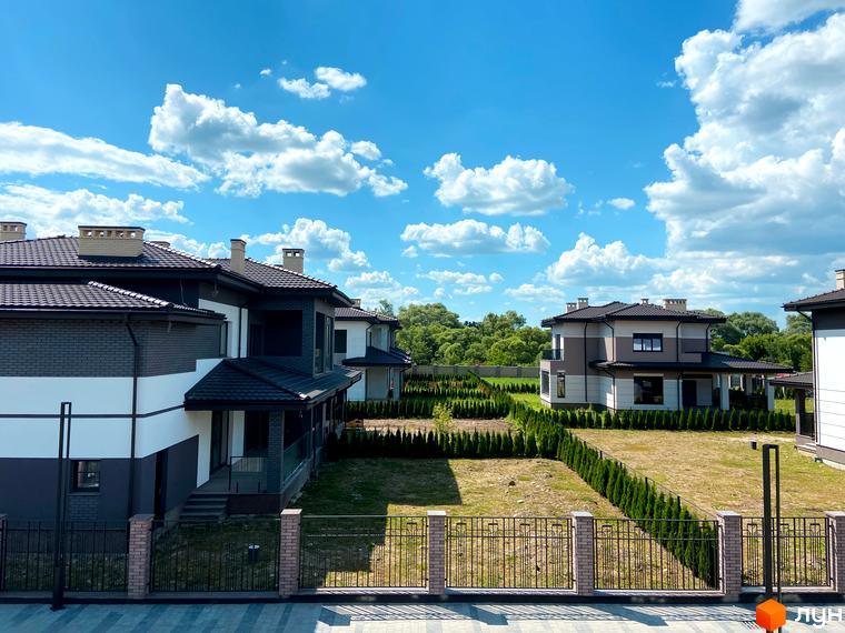 Котеджне містечко Franko River Club. Сучасні двоповерхові будинки з темними дахами та цегляними фасадами, розташовані серед зелених насаджень та огородженої території.