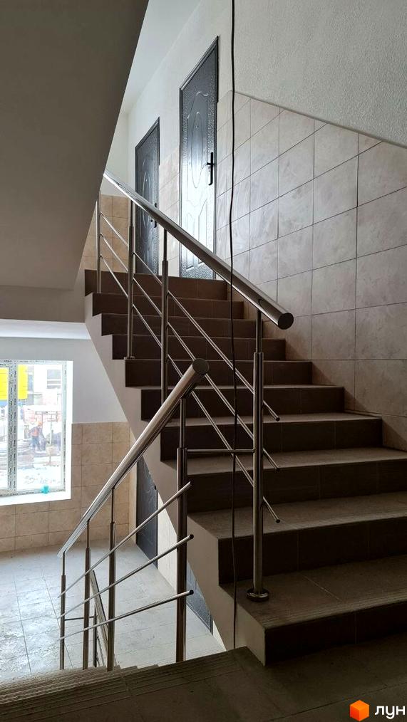Сходи та міжповерхові майданчики у Житловому комплексі Парус. Видно металеві поручні та оздоблення стін плиткою.