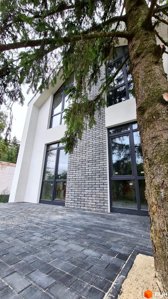 Котеджне містечко ForestHouse: будинок з білим фасадом, сірою цегляною кладкою та великими вікнами. Перед будинком викладена темно-сіра бруківка.