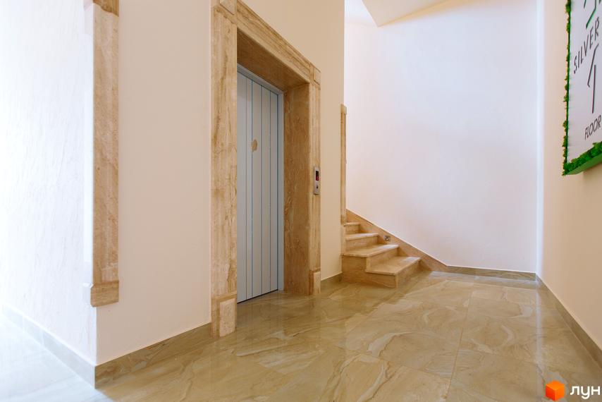 Сучасний вхід до ліфта та сходи в житловому комплексі SilverPark. Світлий хол з мармуровим оздобленням створює відчуття простору та елегантності.