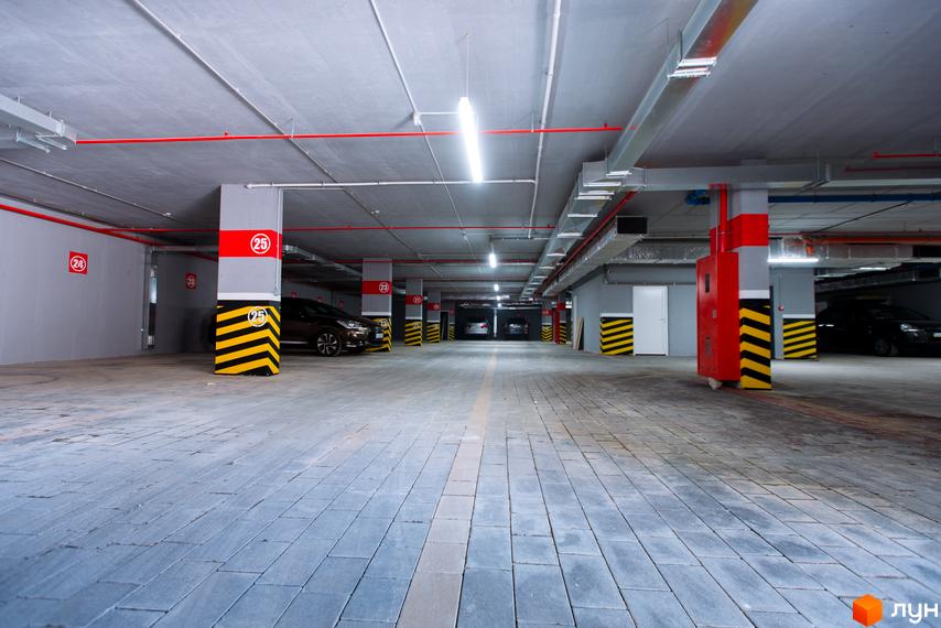 Підземний паркінг житлового комплексу SilverPark з позначеними місцями та системами безпеки. Просторий паркінг з бетонною підлогою та колонами, що забезпечує зручне зберігання автомобілів.