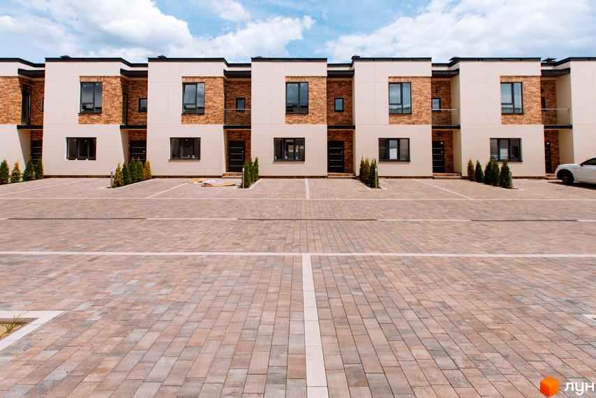 Двоповерхові будинки Котеджного містечка Малиновий з комбінованими фасадами та темними вікнами. Облаштована прибудинкова територія з паркувальними місцями.