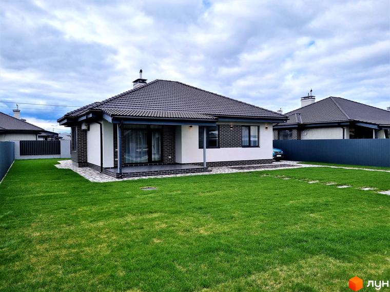 Котеджне містечко Сонячний: одноповерховий будинок з сірим дахом та білими стінами, прибудинкова територія з зеленим газоном та доріжками.