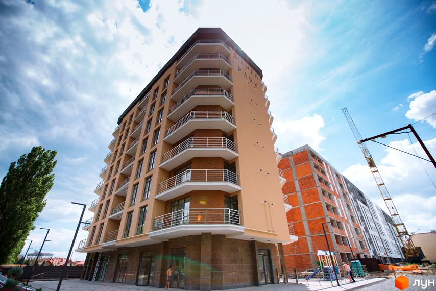 Фасад житлового комплексу SilverPark з численними балконами та вікнами на тлі хмарного неба. Поруч видно будівельний кран та іншу новобудову.