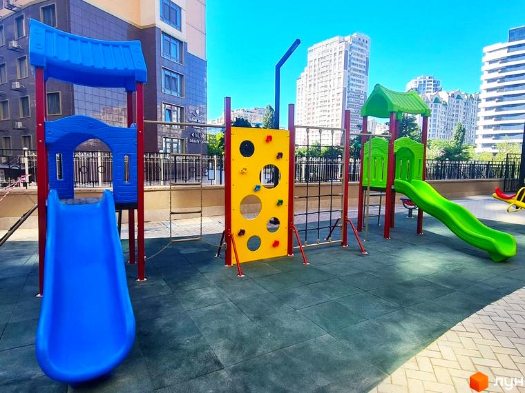 Житловий комплекс Родос має високі будівлі з багатьма вікнами. На прибудинковій території розташований дитячий майданчик з яскравими гірками та ігровим обладнанням.