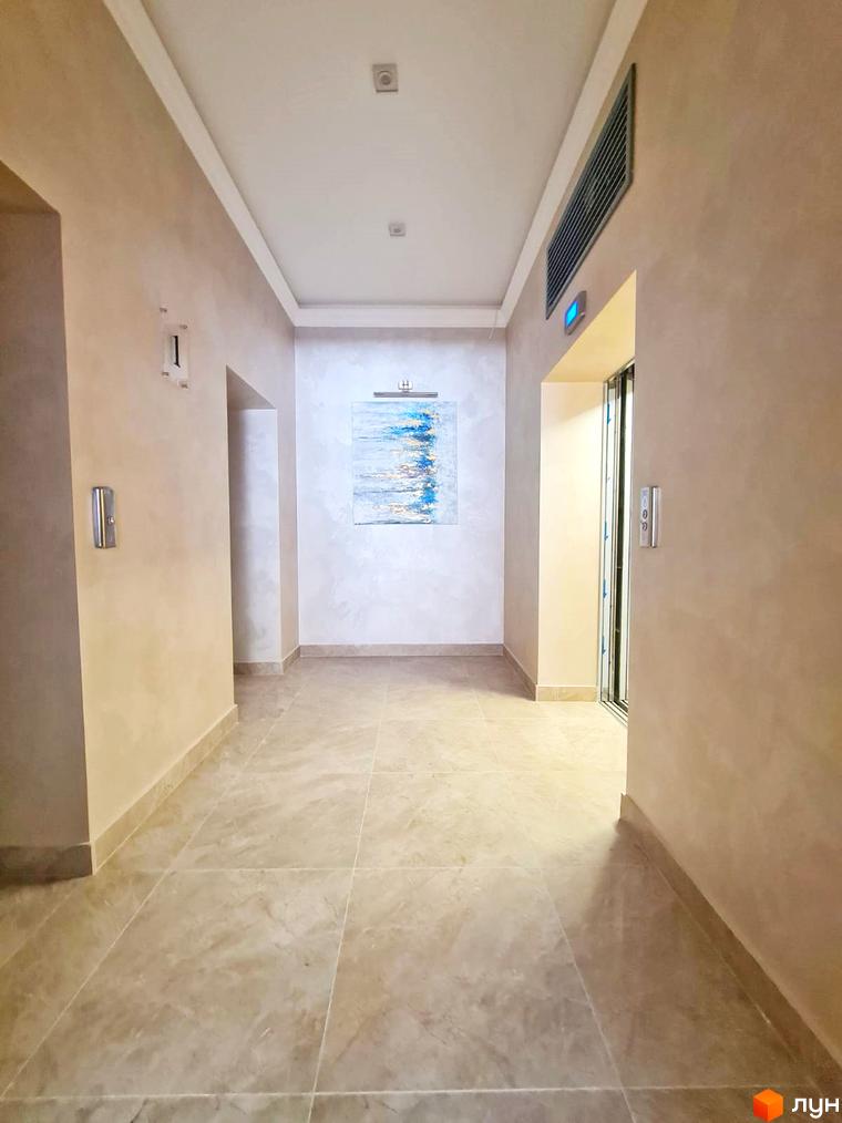 Коридор в ЖК Родос. Світлий інтер'єр з картиною на стіні та мармуровою підлогою. Ліфт та двері в коридорі.