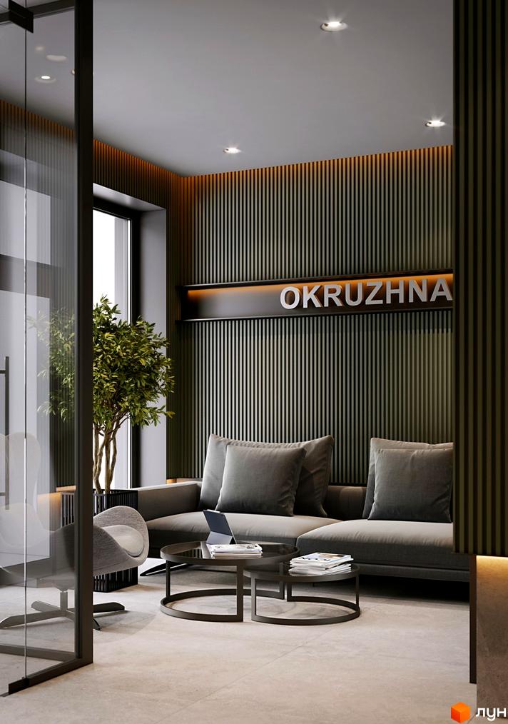 Зона очікування у житловому комплексі OKRUZHNA HALL з диваном, столиками та стіною з написом OKRUZHNA.