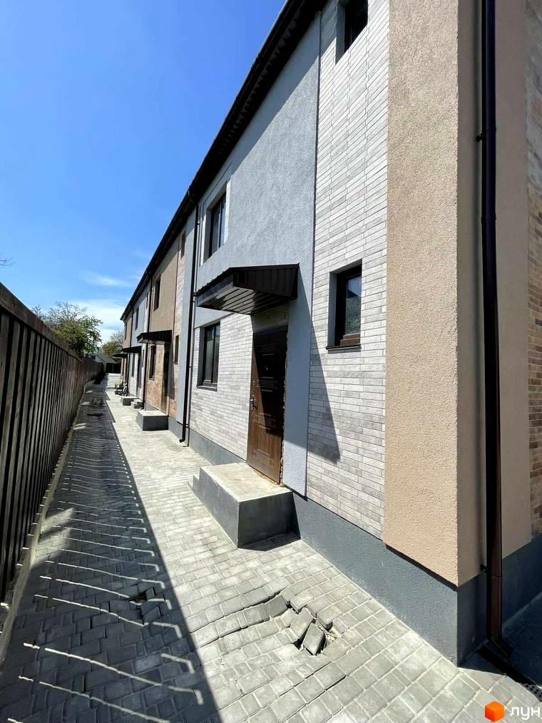 Зовнішній вигляд таунхаусів Comfort home з цегляним фасадом та прибудинковою територією з тротуарної плитки.