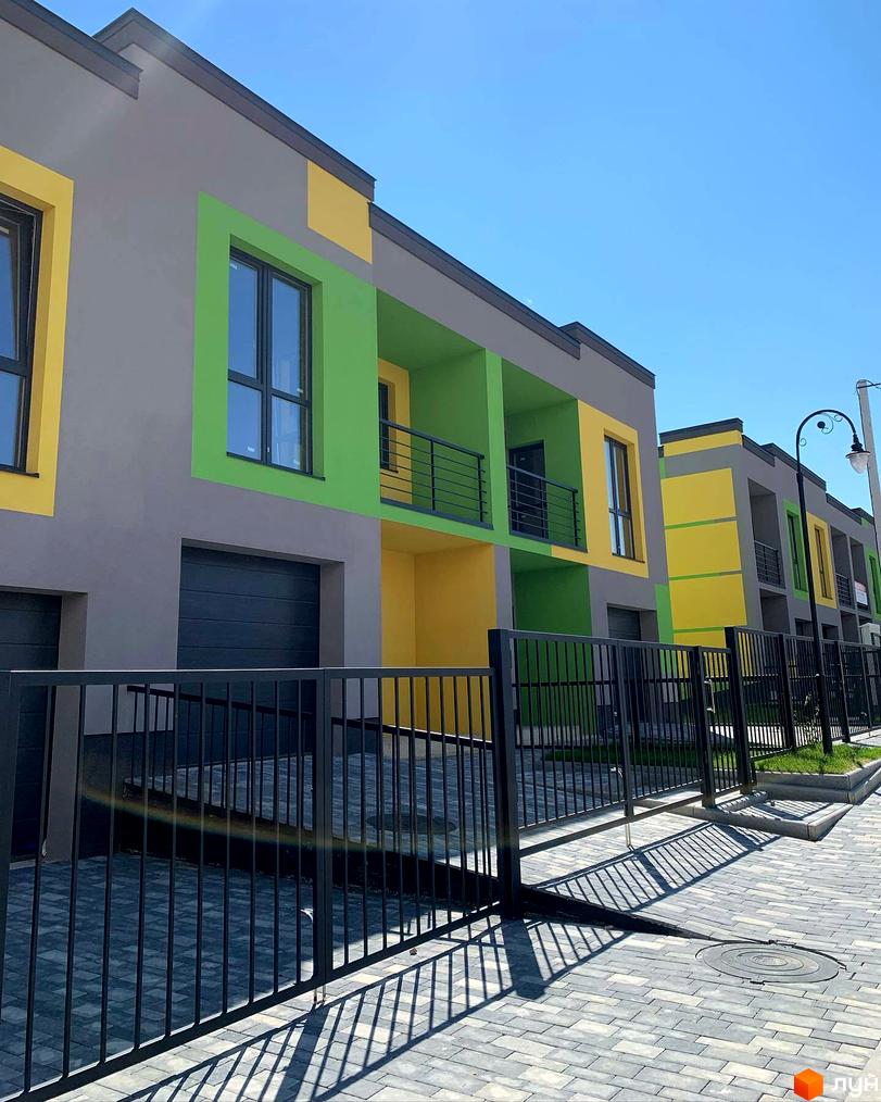 Котеджне містечко КМ Дем’янів лаз. Зовнішній вигляд будинків з яскравими фасадами та прибудинкова територія з бруківкою та парканом.