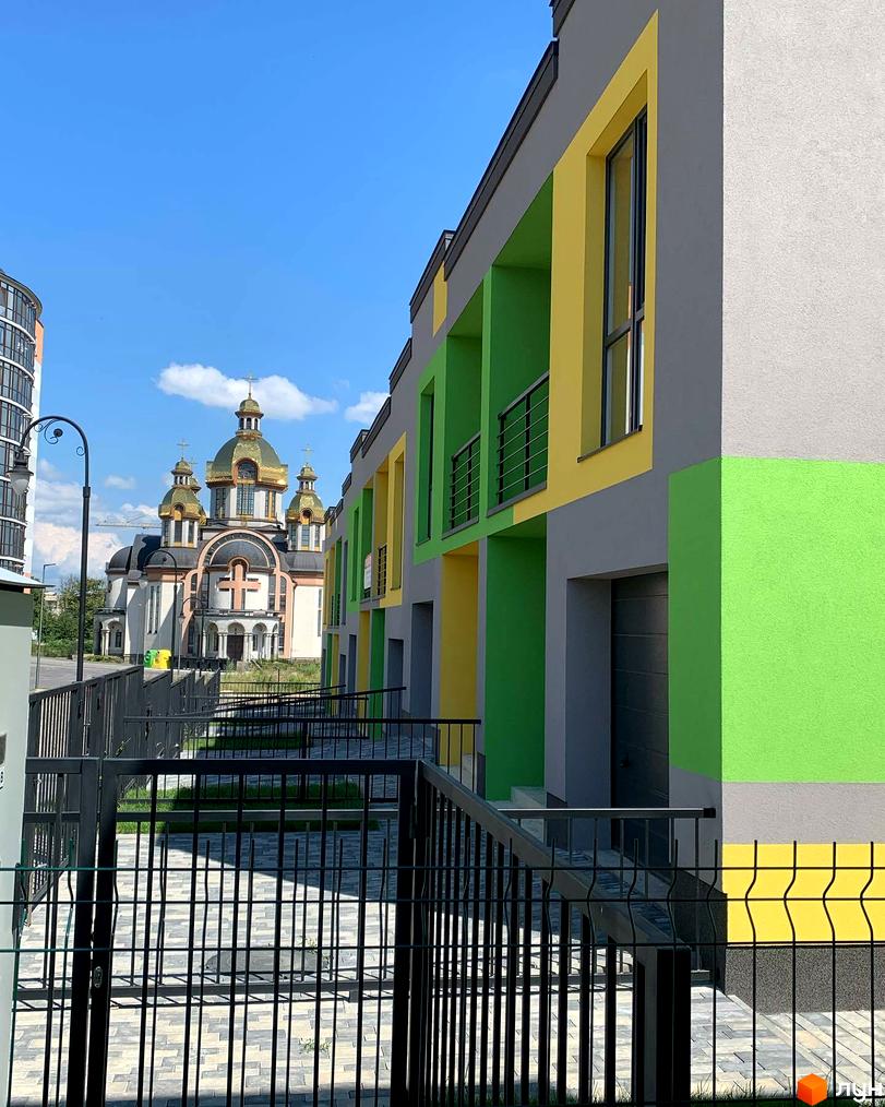 Котеджі Котеджного комплексу Дем’янів лаз мають сірі фасади з жовтими та зеленими вставками. Прибудинкова територія має чорні огорожі та бруківку.