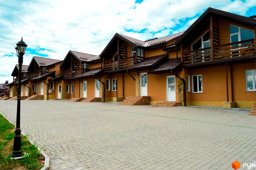 Таунхауси „Андора“ – двоповерхові будинки з коричневими дахами та терасами, розташовані на вимощеному подвір'ї з ліхтарем.