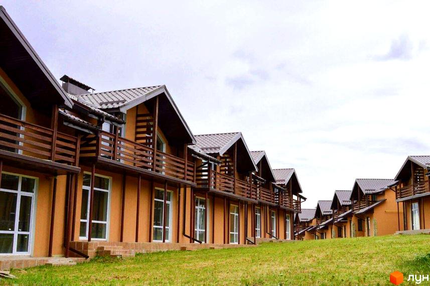 Зображення таунхаусів „Андора“ з балконами та дахами з металочерепиці. Перед будинками зелений газон.