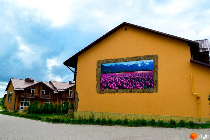 Фасад таунхаусів „Андора“ з великим зображенням тюльпанів. Будинки з коричневими дахами та світлими стінами, доглянута територія.