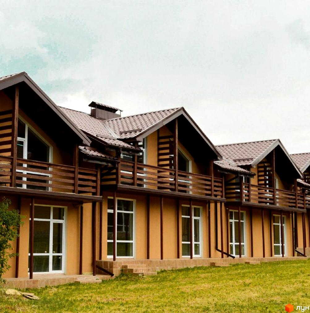 Зовнішній вигляд таунхаусів „Андора“ з коричневим дахом та дерев'яними балконами. Навколо будинків зелений газон.