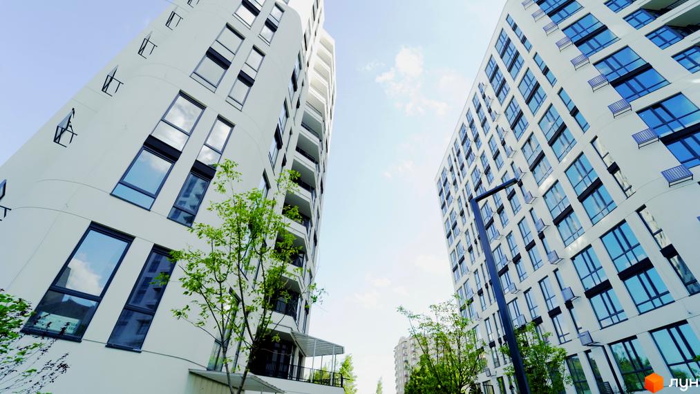 Вид на висотні будинки Житлового комплексу Лісопарковий з великими вікнами та зеленими насадженнями на передньому плані.