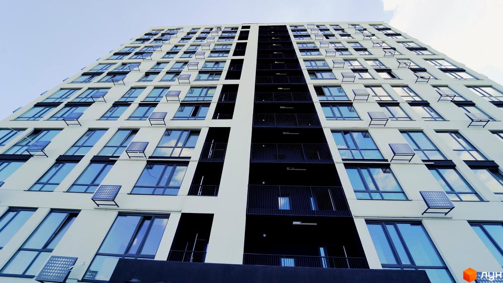 Вид на багатоповерховий будинок Житлового комплексу Лісопарковий з великими вікнами та балконами. Сучасна архітектура новобудови.