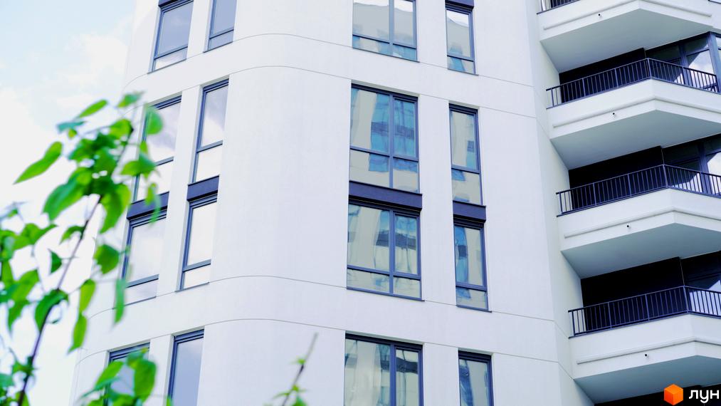 Зображення фасаду багатоповерхового будинку в Житловому комплексі Лісопарковий з великими вікнами та балконами.
