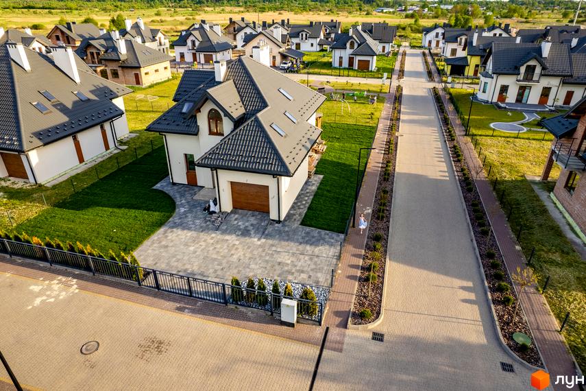 Котеджне містечко Praud Hills. Сучасні будинки з сірими дахами та білими стінами, доглянута прибудинкова територія з газонами та бруківкою.