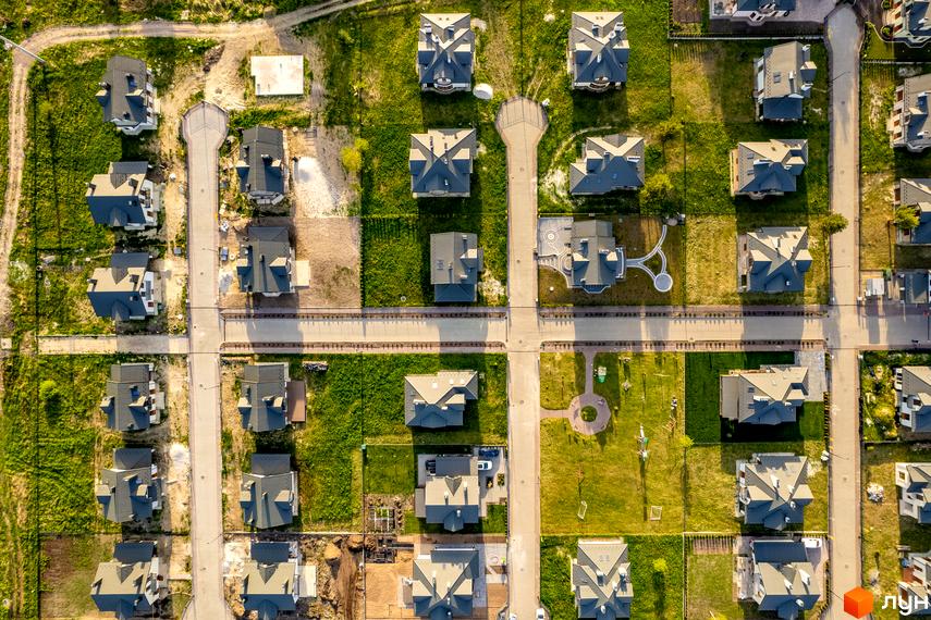 Котеджне містечко КМ Praud Hills. Аерофотозйомка котеджів з сірими дахами та прибудинковою територією з зеленими газонами та доріжками.