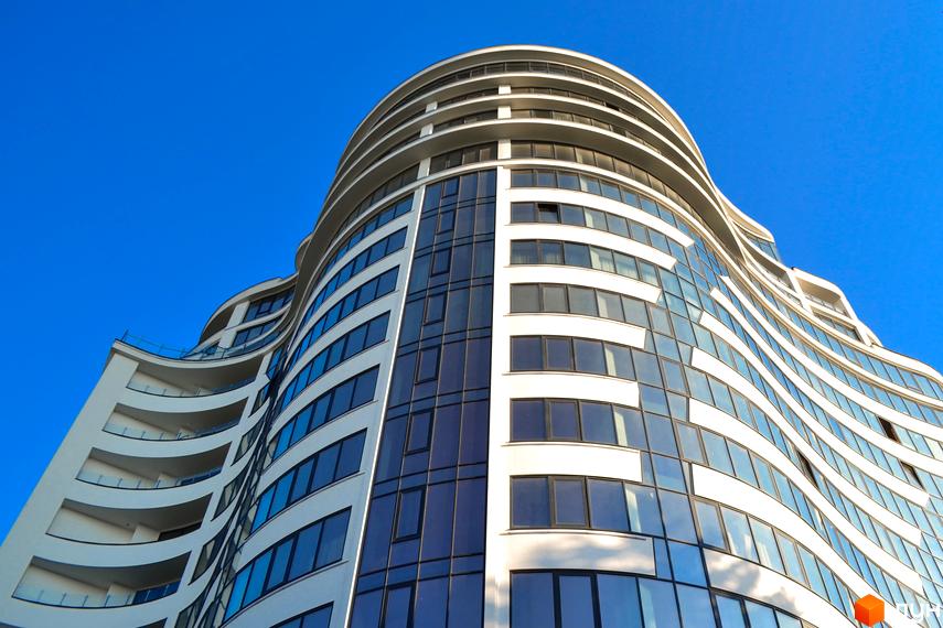 Зображення фасаду житлового комплексу Parus з великою кількістю вікон. Видно частину прибудинкової території та блакитне небо.