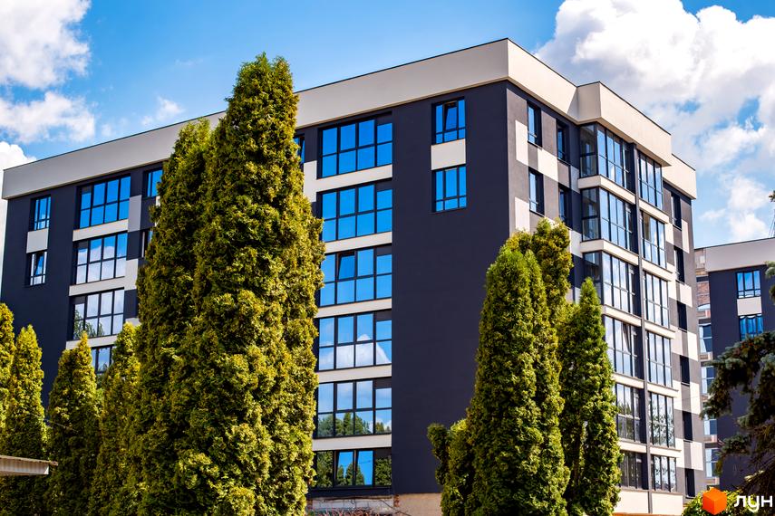Багатоповерховий будинок Житлового комплексу Union з темно-сірими фасадами та великими вікнами. Перед ним ростуть високі зелені дерева.