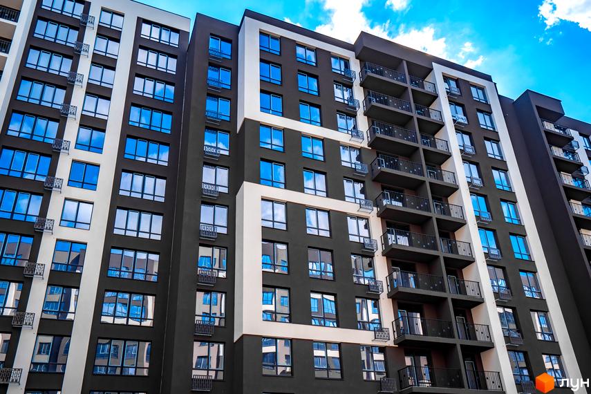 Зовнішній вигляд багатоповерхового будинку в Житловому комплексі Паркова Алея. Фасад з великими вікнами та балконами, частина будинку пофарбована у білий колір.