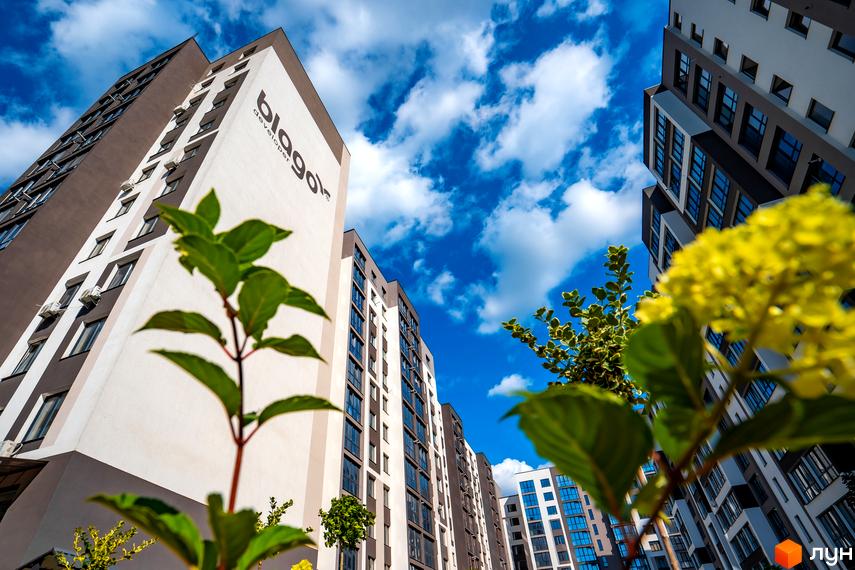 Фото фасаду та прибудинкової території Житлового комплексу Паркова Алея на фоні блакитного неба. Вигляд багатоповерхового будинку ззовні.