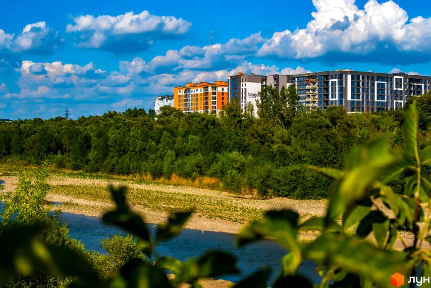 Зображення житлового комплексу Паркова Алея з видом на річку та зелені насадження. На задньому плані видно багатоповерхові будинки.