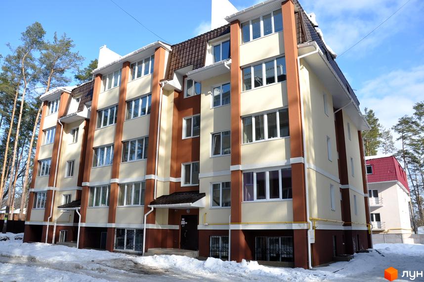 Житловий комплекс Спарта з фасадом у світлих тонах, оточений зеленими деревами та засніженою територією.