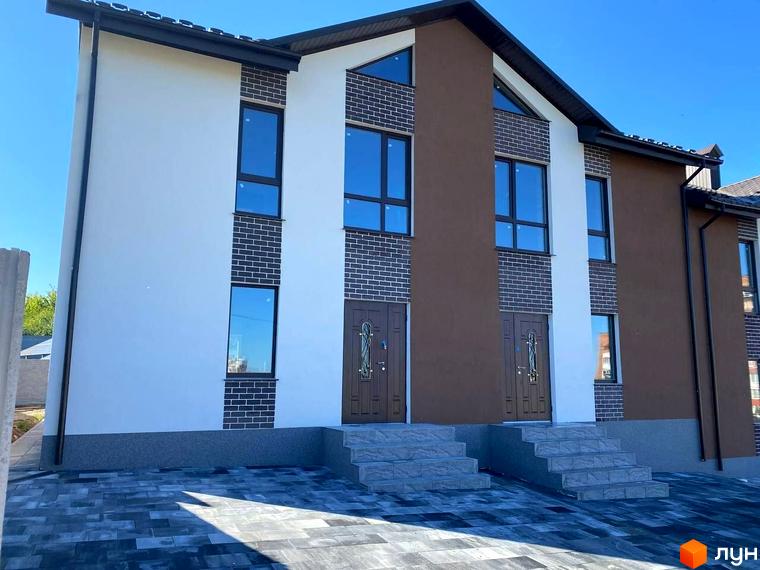 Фасад таунхаусів Dream Town 3 має білі та коричневі стіни з цегляними елементами. Перед будинками бруківка та сходи до двох вхідних дверей.