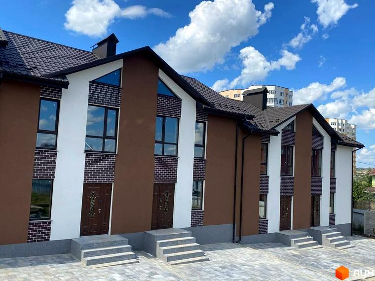 Зображення таунхаусів Dream Town 3 з коричнево-білими фасадами, цегляними вставками та бруківкою перед входом.