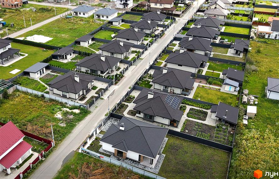 Котеджне містечко Сонячний: сучасні будинки з темними дахами та доглянутими ділянками. Аерофотозйомка новобудов з зеленими газонами та парканами.