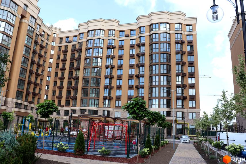 Житловий комплекс Sofia Nova з фасадом світло-бежевого кольору та великою кількістю вікон. На території розташований дитячий майданчик з елементами для ігор.