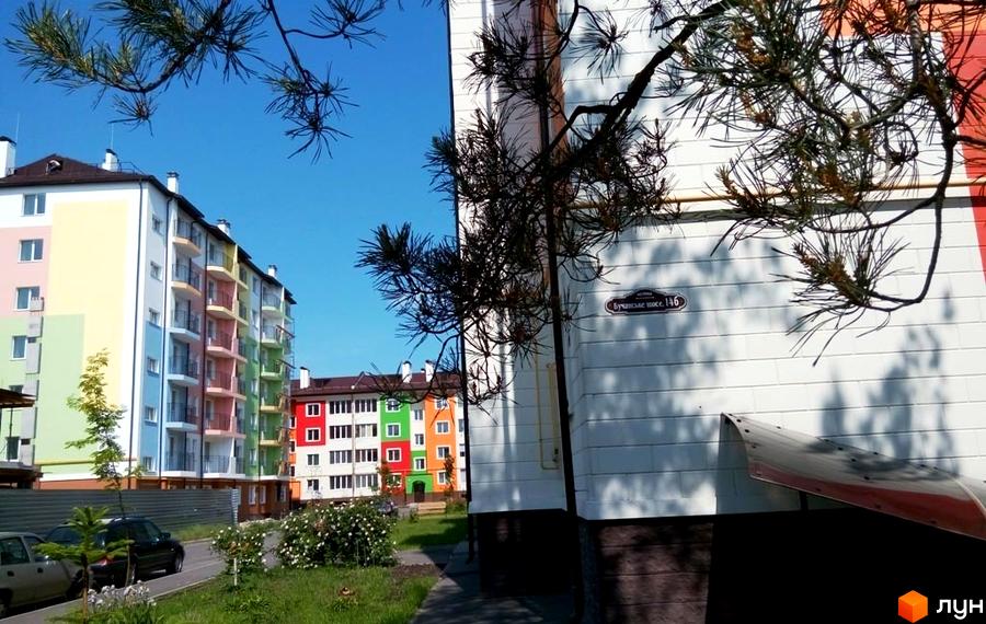 Житловий комплекс Ягода з кольоровими фасадами будинків та прибудинковою територією, озелененою квітами та деревами.