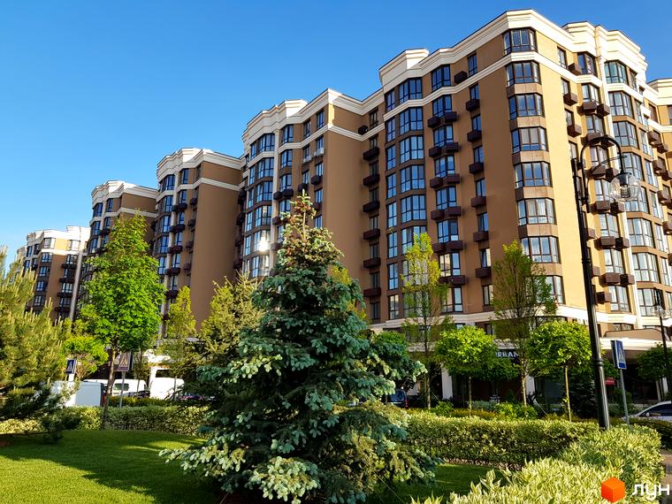 Фото фасаду та прибудинкової території Житлового комплексу Sofia Residence. Багатоповерховий будинок з великими вікнами, зелені насадження.
