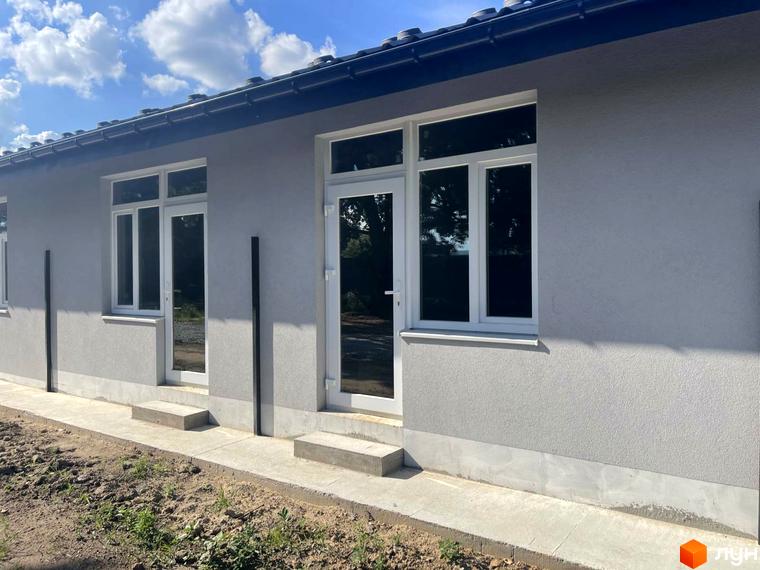 Зовнішній вигляд будинку житлового комплексу Оак-Парк з вікнами та дверима. Навколо будинку облаштована прибудинкова територія з бетонною доріжкою та землею.