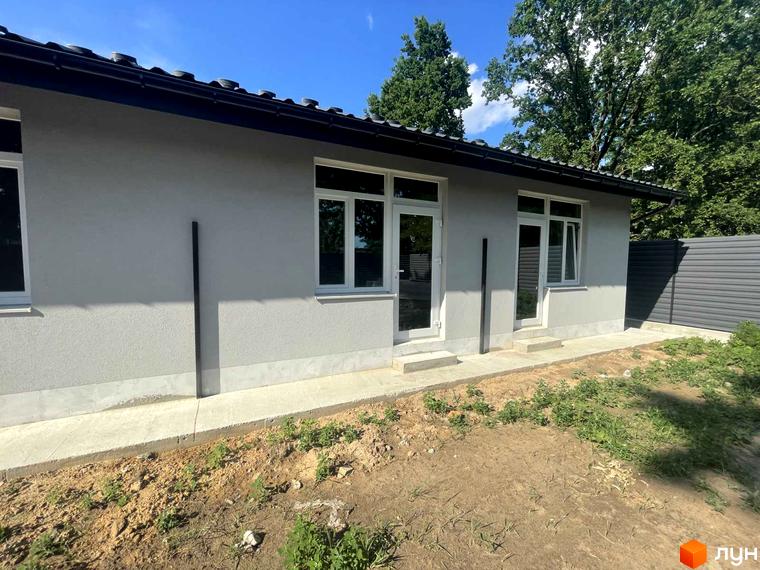 Будинок з сірими стінами та білими вікнами в Таунхауси Оак-Парк. Поруч розташована прибудинкова територія з травою та парканом.