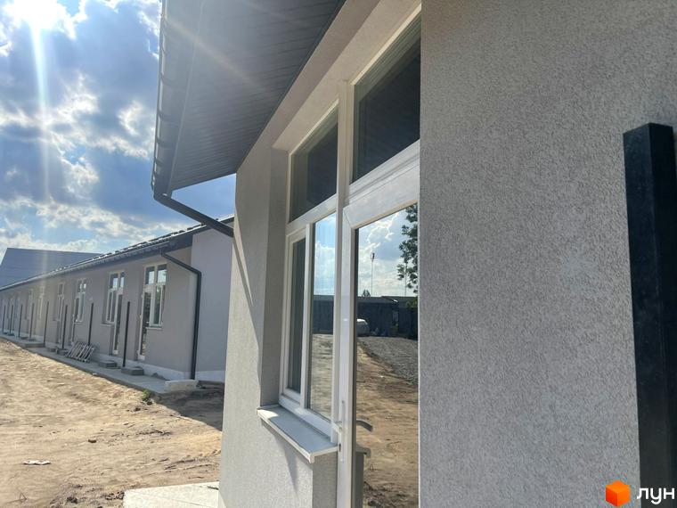 Зовнішній вигляд таунхаусів Oak-Park з білою штукатуркою та вікнами. Навколо новобудови піщана територія під час будівництва.