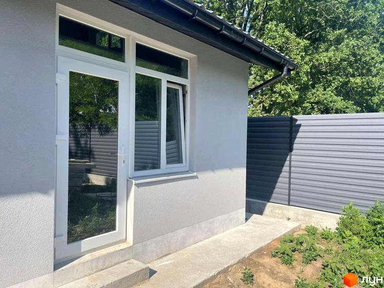 Зовнішній вигляд будинку з білими вікнами та дверима, поруч сітчастий паркан та зелені насадження. Таунхауси Оак-Парк.