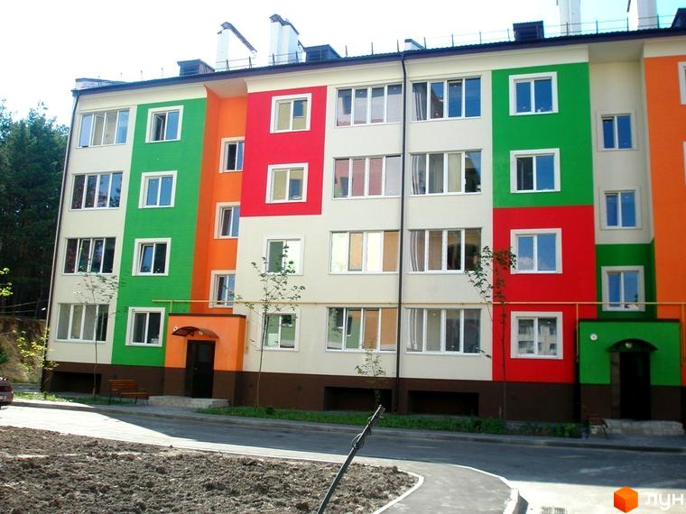 Житловий комплекс Ягода з яскравими кольоровими фасадами та прибудинковою територією, озелененою молодими деревами.
