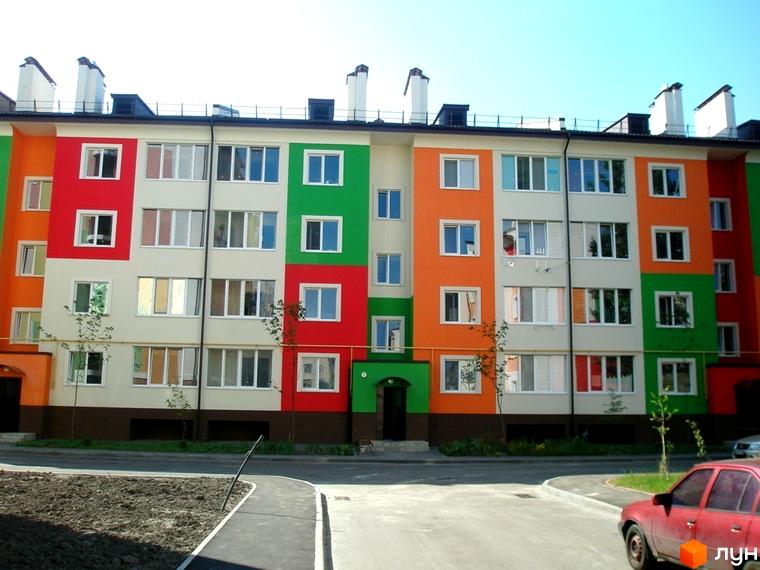 Житловий комплекс Ягода з яскравими фасадами, прибудинкова територія з асфальтованими доріжками та зеленими насадженнями.