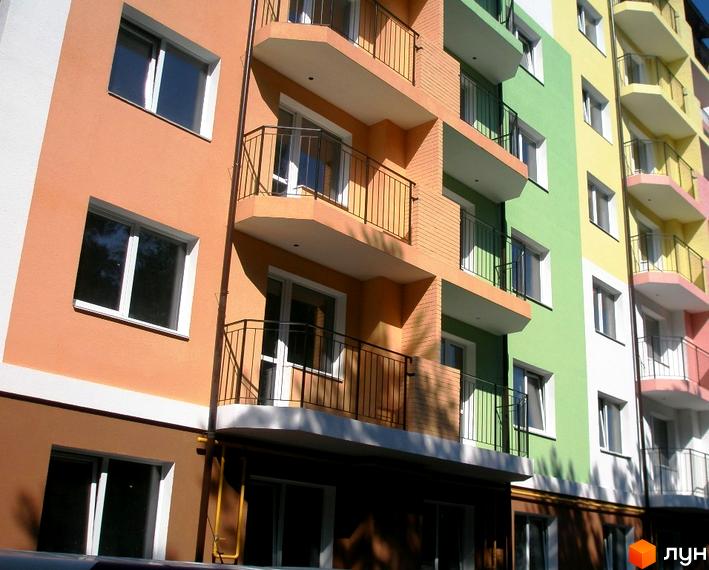 Фасад житлового комплексу ЖК Ягода з різнокольоровими секціями: персиковою, зеленою та жовтою. Видно балкони з чорними огорожами та вікна.