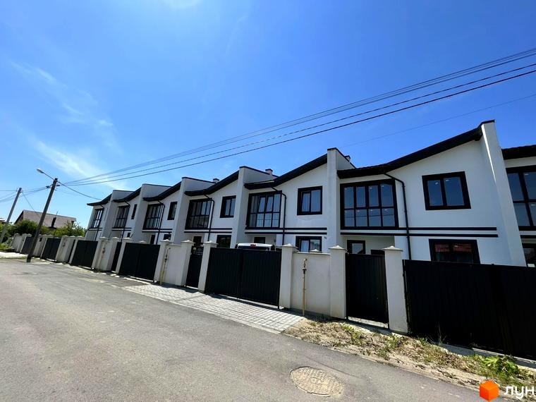 Таунхауси BalHous: білі двоповерхові будинки з чорними вікнами та дахом, огороджені парканом. Зовнішній вигляд новобудови та прибудинкової території.