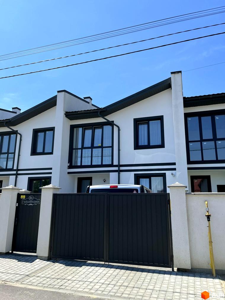 Зовнішній вигляд таунхаусів BalHous з чорними вікнами та сірою огорожею. Вигляд на фасад та прибудинкову територію.