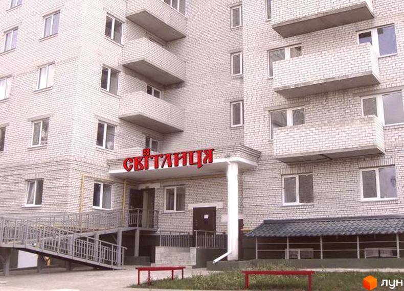 Зовнішній вигляд будинку ЖК Світлиця з червоною вивіскою та прибудинковою територією з зеленими насадженнями.