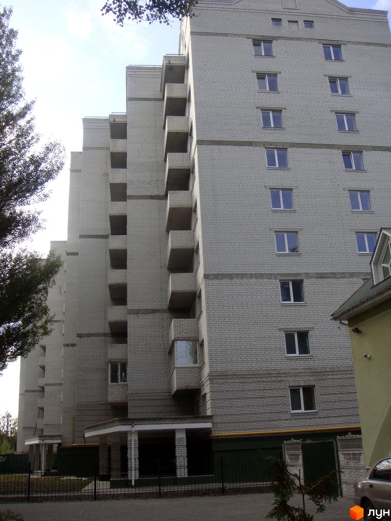 Житловий комплекс Світлиця з фасадом з білої цегли та балконами. Прибудинкова територія з зеленими насадженнями та паркувальними місцями.