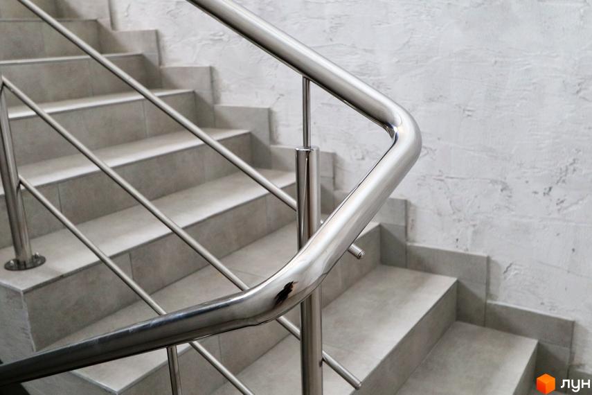 Сходи з металевим поручнем у ЖК Central House. Сучасний дизайн сходів з сірою плиткою та полірованим поручнем.