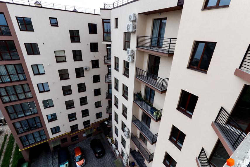 Фасад житлового комплексу Central House з численними вікнами та балконами, видно прибудинкову територію з автомобілями.