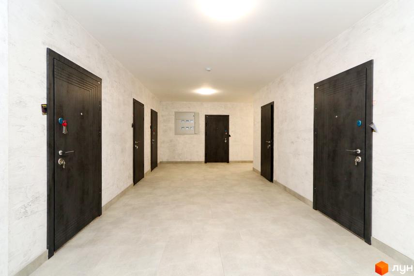 Коридор з дверима в ЖК Central House. Вхідні двері темного кольору, стіни світлі з текстурою.